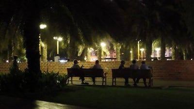 Recalling the old days: people chat on the benches in a grassy area of the park in Karama.