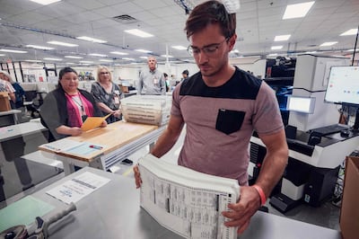 An election worker processes a stack of 2024 general election ballots with the tabulation machine in front of observers. AFP