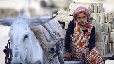 An Iraqi girl rides a cart carrying bricks as she works at a brick factory near the central Iraqi shrine city of Najaf. Five out of seven brick factories in the region have been hit by flood water following heavy rainfall. Haider Hamdani / AFP