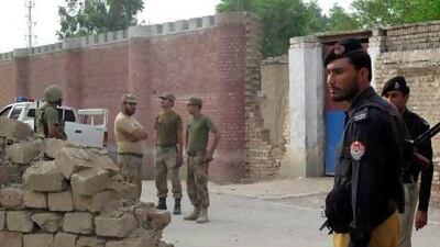 Policemen (right) and soldiers (left) stand outside a prison following a Taliban attack and mass breakout in Dera Ismail Khan.