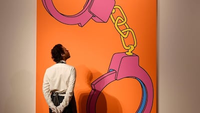 An employee poses as he views 'Handcuffs' by Michael Craig-Martin ahead of the George Michael online auction at Christie's. Reuters