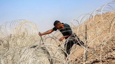 A man attempts to remove parts of the barbed-wire fence of the so-called 'Netzarim corridor' near Nuseirat, as people make their way back to Gaza city. AFP