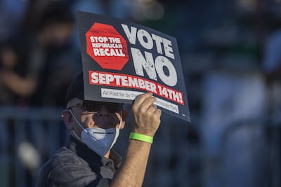 A supporter holds a sign before Mr Newsom and Mr Biden arrive to campaign to keep the governor in office at Long Beach City College. AFP