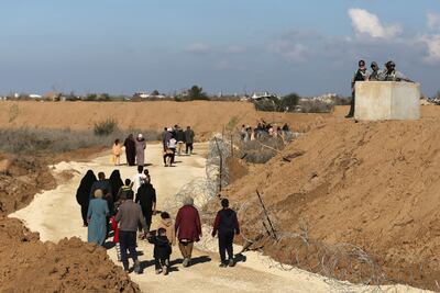 Foreign security personnel observe displaced Palestinians as they return from the south to their homes in northern Gaza. Reuters