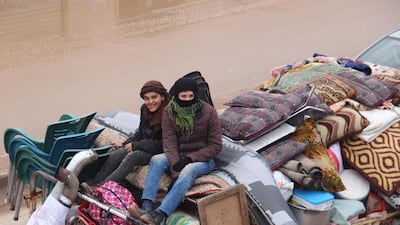 Syrian youths sit in the back of a truck loaded with belongings, passing through the town of Hazano in Idlib's northern countryside. AFP