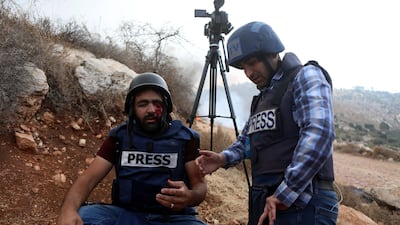 A colleague assists Palestinian cameraman Muath Amarneh after he was shot in the eye by Israeli troops. EPA