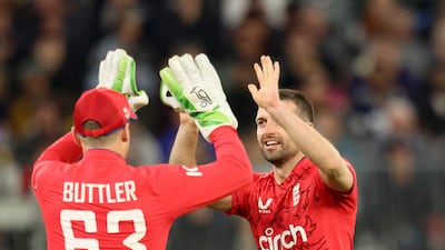 England captain Jos Buttler celebrates with Mark Wood after the dismissal of Australia batter Tim David for a duck. AFP