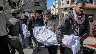 Men carry the bodies of people killed when Israeli forces opened fire on crowds rushing at an aid distribution point in Gaza City on February 29, 2024. AFP