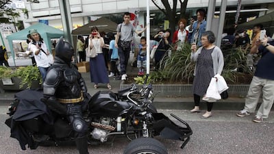 People take pictures of a 41-year-old man going by the name of Chibatman sitting on his Chibatpod.