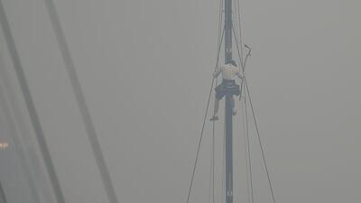 A sailor climbs the mast of a yacht enveloped in haze caused by nearby bushfires at the Cruising Yacht Club of Australia in Sydney. AFP