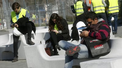 People use their mobile phones near the entrance to the Mobile World Congress in Barcelona. Albert Gea / Reuters