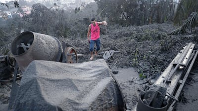 A man walks along ash fall covered plants and equipment as Taal Volcano continues to spew ash on Monday. AP Photo