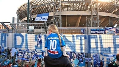 A girl looks at the memorabilia placed outside the San Paolo stadium in Naples in memory of Diego Maradona. AP