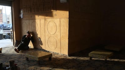 A restaurant worker sits among empty tables as he waits for customers in Siwa.