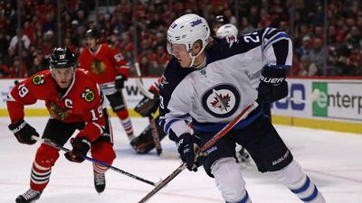 Patrik Laine of the Winnipeg Jets looks to pass as Jonathan Toews of the Chicago Blackhawks closes in. Jonathan Daniel / AFP