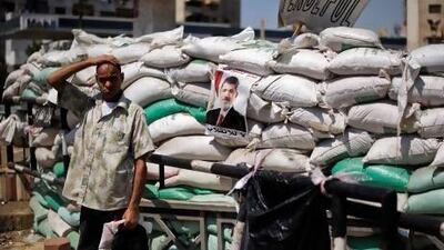 An Egyptian man stands by a defensive barrier made of sandbags near a protest by members of Egypt's Muslim Brotherhood.