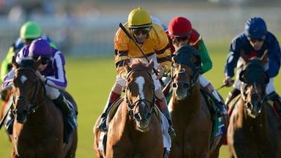 Jockey John Velazquez, centre, stands up as he rides Wise Dan across the finishing line at the Breeders' Cup Mile.