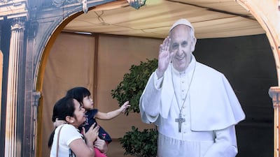 A girl reaches out to touch a cutout of the Pope at St Mary's Catholic Church in Dubai. All photos by Leslie Pableo for The National