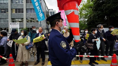 A police officer holds traffic cones as people protest against government's decision to start releasing massive amounts of treated radioactive water from the wrecked Fukushima nuclear plant into the sea. AP
