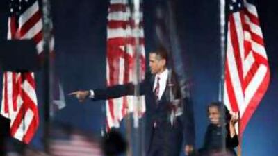 Barack Obama, the US president-elect, and his daughter, Sasha, are seen through bulletproof glass at his election night rally in Chicago.