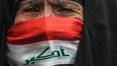 An elderly Iraqi woman, her face covered with a national flag, cries as she watches anti-government demonstrators protesting in the capital Baghdad's Tahrir square. AFP