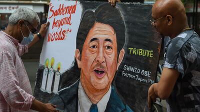 Artists carry a painting of Mr Abe in Mumbai. AFP