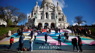 Tourists stand on the Sacre-Coeur Basilica stairs painted with the Paris 2024 Olympic and Paralympic Games colours. Reuters