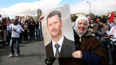 Syrians wave national flags and portraits of President Bashar Al Assad in support of the regime on the first anniversary of the anti-regime revolt in Damascus.