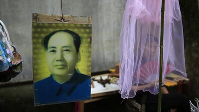 A souvenir hawker fans herself behind a veil at her stall selling Mao Zedong souvenirs outside the ‘Water Dripping Cave’ compound, where Mao Zedong stayed briefly for 11 days in 1966 and is thought to have contemplated the start of the Cultural Revolution there in Shaoshan, Hunan Province in central China. How Hwee Young / EPA