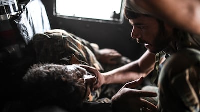A member of the SDF comforts his wounded comrade after the latter was shot by a sniper on the eastern frontline of Raqqa, in September 2017. AFP