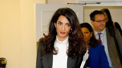 Amal Clooney, wearing a pinstriped suit, attends a press conference at Doughty Street Chambers on October 5, 2015 in London. Getty Images