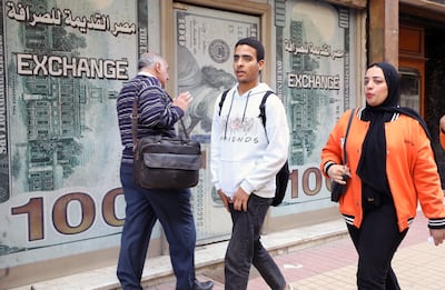 Egyptians walk past a currency exchange office in Cairo. EPA