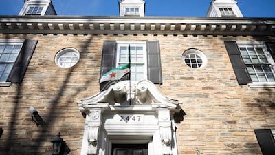 The new national flag of Syria is seen at the former Syrian ambassador's residence in Washington. Wildly overgrown vegetation outside an empty building was finally pruned away in September as the flag of Syria was raised