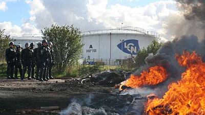 French anti-riot policemen walk inside a fuel storage depot blocked by strikers. Kenzo Tribouillard / AFP