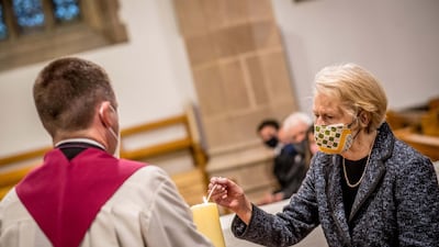 Pat Hume, right, lights a candle at St Eugene's Cathedral. Getty Images