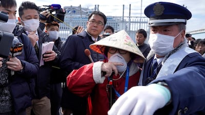 A passenger of the Diamond Princess cruise ship is surrounded by members of the media, as she leaves the Daikoku Pier Cruise Terminal in Yokohama, south of Tokyo. EPA
