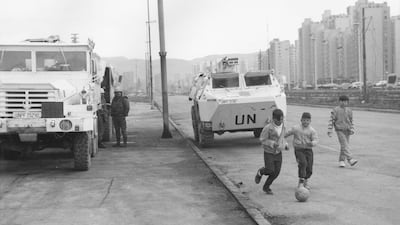 Children playing football beside UN vehicles parked in Sarajevo in September 1993. Getty Images