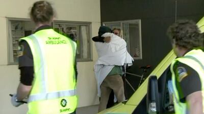 One of the two rescued hikers, wrapped in a white blanket, receives a hug as they enter a hospital in Nelson, New Zealand on May 27, 2020. Newshub/TVNZ via AP