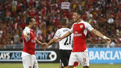 Arsenal's Mesut Oezil celebrates with teammate Santi Cazorla after scoring their third goal against Everton on Saturday in Singapore. Wallace Woon / EPA
