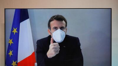 Emmanuel Macron seen on a screen as he attends by video conference a round table for the National Humanitarian Conference.