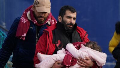 A man thought to be a migrant carries a small child after they were brought in to Dover, Kent, following a small boat incident in the Channel. PA