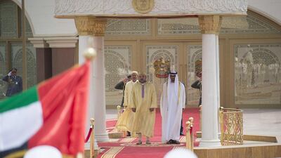 Sheikh Mohammed bin Zayed, right, King Mohammed VI of Morocco, left, and Prince Moulay Rachid of Morocco, back left, stand for the UAE national anthem during a reception at Mushrif Palace. Rashed Al Mansoori / Crown Prince Court - Abu Dhabi