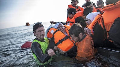 A Syrian refugee is helped by volunteers to leave a sinking dinghy at a beach on the southeastern island of Lesbos on February 28, 2016. Manu Brabo/AP Photo