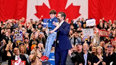 Conservative Party of Canada leader Pierre Poilievre lifts a child dressed in a police costume at a rally in Surrey, British Columbia, Canada. Reuters