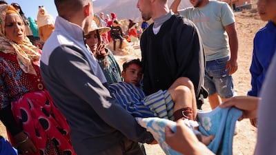 An injured child is carried by neighbours in the village of Ighil Ntalghoumt. Reuters