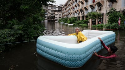 A woman is pulled through the floodwater in Bangkok on an inflatable boat. AFP