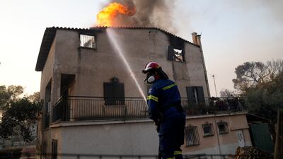 A firefighter tries to extinguish flames at a burning house in Varibobi, northern Athens.