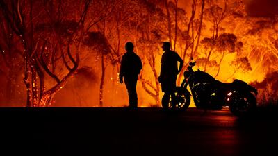 Residents look on as flames burn through bush in Lake Tabourie, Australia. Getty