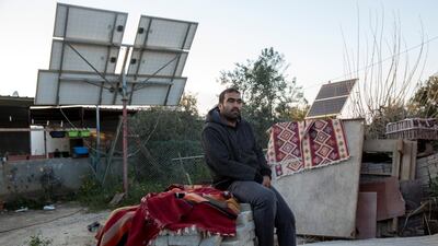Mohamed Abu Queder ,35, sits on a pile of cement construction blocks and traditional carpets and solar panels in the unrecognised village of Zarnuk near the southern Israeli city of Beersheba. Unrecognised illegal villages like this one have scarce access to water, electricity and other services. (Photo by Heidi Levine for The National).