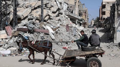 Palestinian boys ride a donkey-pulled cart near a building destroyed in an Israeli bombardment in Rafah in the south of the Gaza Strip. AFP